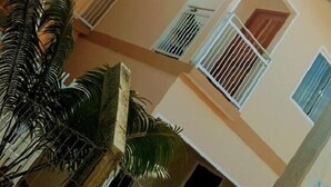 A multi-story building with balconies, a staircase, and a palm tree. - Pousada Cordeiro (Penha)