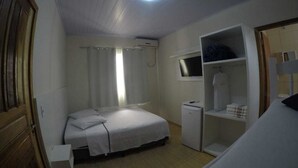 A bedroom with a bed, a small desk, a TV mounted on the wall, and a wardrobe. - Pousada Cordeiro (Penha)