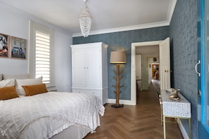Un dormitorio con cama, armario blanco, lámpara y pared azul.
