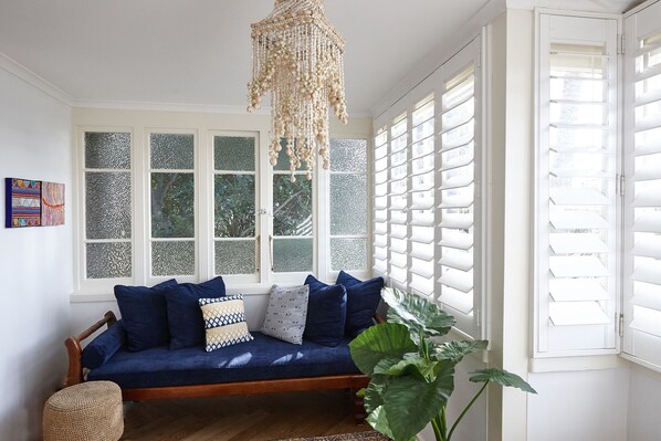 Una habitación acogedora con un sofá azul, un pouf tejido y una planta verde grande.