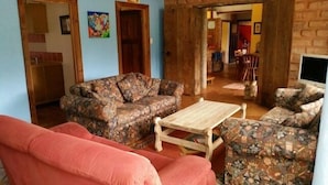 Ein Wohnzimmer mit einem gemusterten Sofa, einem Holztisch und einem roten Schlafsofa.