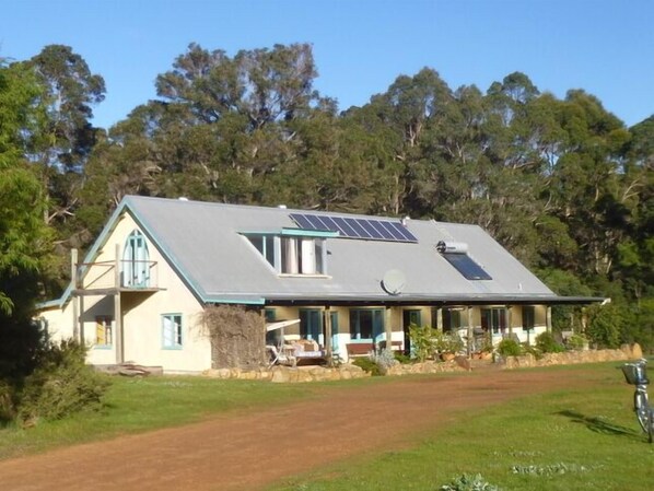 A two-story house with a sloped roof, solar panels, and a covered porch.