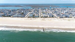 Vista aérea de un pueblo costero con propiedades frente a la playa, una playa y un tanque de agua a lo lejos.
