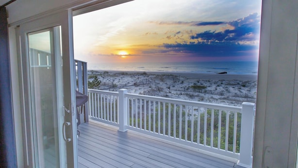 Una terraza con vista a una playa al atardecer.
