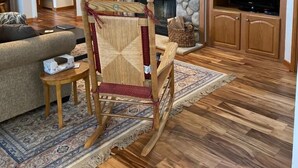A cozy living room with a stone fireplace, wooden furniture, and a television. - Escape To The Country In Comfort And Style In An Eco-Friendly House (Rushville)