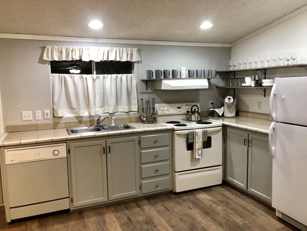 Kitchen area with a stove, sink, and refrigerator, offering ample space for cooking and storage.