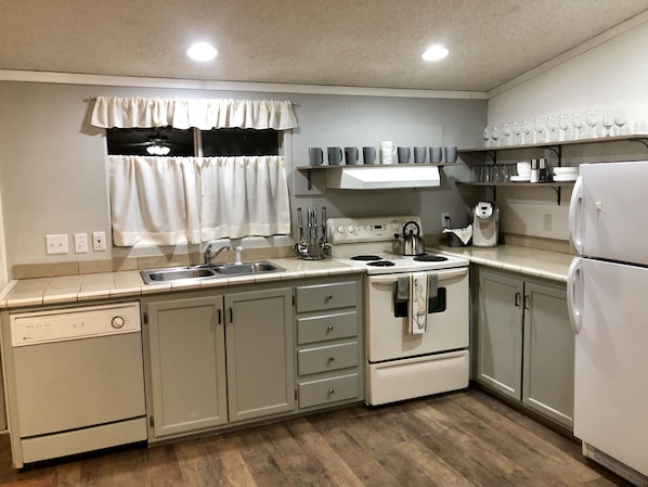 Kitchen area with a stove, sink, and refrigerator, offering ample space for cooking and storage.