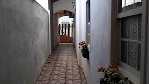 Un corridoio stretto con pavimento in pietra, pareti bianche e soffitto in legno.