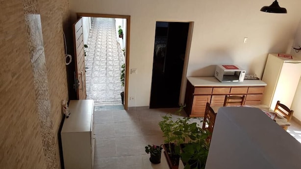 Una stanza con un letto, una scrivania, una sedia, un piccolo armadio e una pianta in vaso.