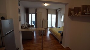 A compact room with a kitchenette, a bed, and a small table.