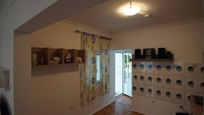 A hallway with wooden shelves, a patterned curtain, and a tiled wall with circular cutouts.