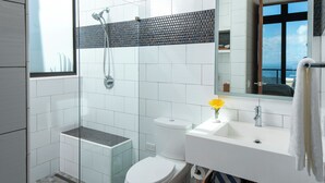 A modern bathroom with a glass-enclosed shower, a white toilet, and a sink with a mirror above it. - The Crown Jewel of Calichi (St. John)