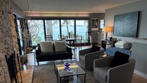 Een moderne woonkamer met een stenen muur, een open haard, een bank, een salontafel en uitzicht op zee.
