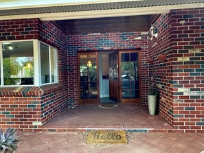 A brick exterior with a sliding glass door, a welcome mat, and a potted plant.