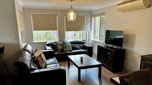 Un salon avec un canapé, une table basse, un téléviseur et une cheminée.