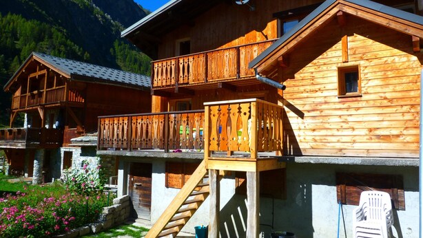 Eine Holzchalet mit Balkon und einer Treppe, die zu einer oberen Ebene führt.