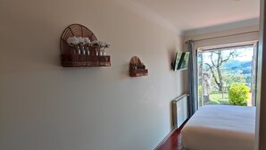 Un dormitorio con un ventanal grande, piso de madera y dos cestas decorativas sujetas a la pared.