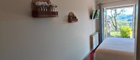A bedroom with a large window, wooden flooring, and two wall-mounted decorative baskets.