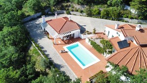 Una propiedad residencial con piscina, edificios con tejados de teja y un jardín.