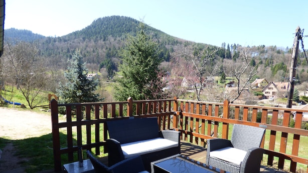 Una terraza con mobiliario exterior y vistas a un paisaje montañoso.