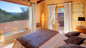 A bedroom with a large bed, leopard print bedding, a view of the outdoors, and a window with curtains.