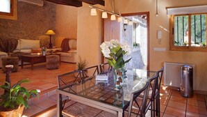 A spacious living area with a glass dining table, comfortable seating, and a view of the outdoors.