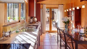 A modern kitchen with a large island, stainless steel appliances, and a dining area with a glass table and chairs.