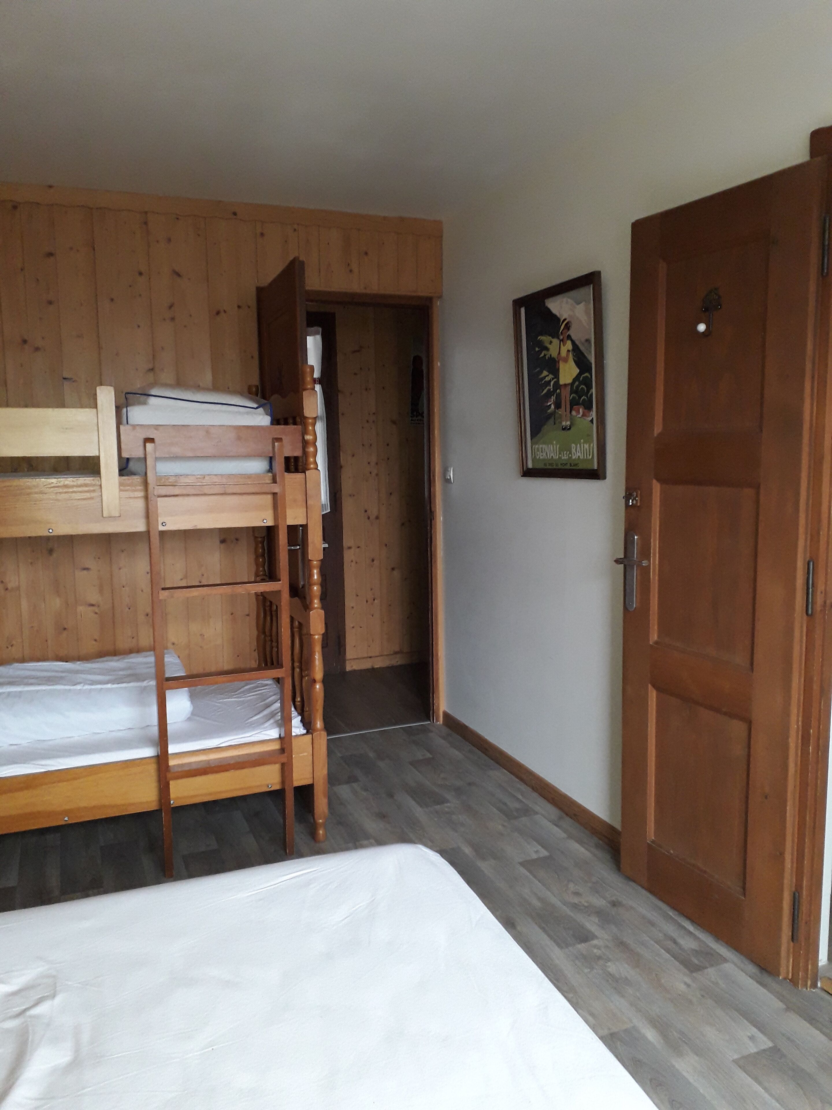 Una habitación con literas, paredes de madera, una puerta y un cartel en la pared.
