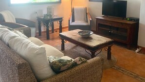 A living room with a sofa, armchair, coffee table, and a television on a wooden cabinet. - Pretty Reformed Stables With Spectacular Country Views, Private Pool And Gardens (El Tropezon, Colmenar)