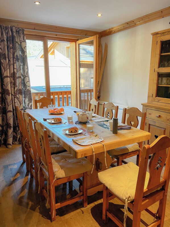 Un espace repas avec une table en bois, des chaises et une vue sur l’extérieur.