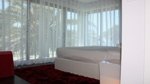 Ein Schlafzimmer mit einem Bett, einem roten Teppich und durchsichtigen Vorhängen.
