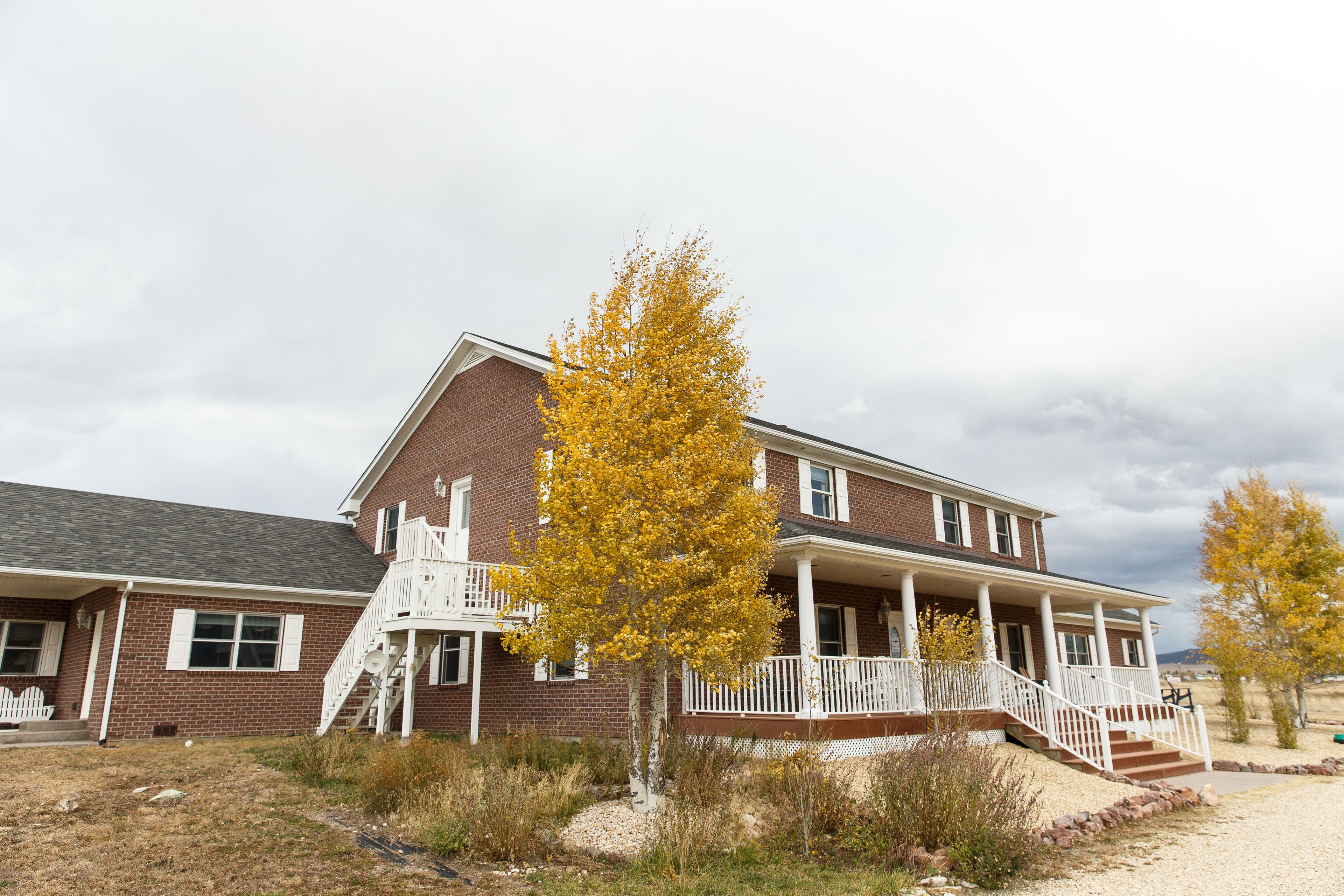 A two-story brick house with a front porch, a staircase, and a small front yard.