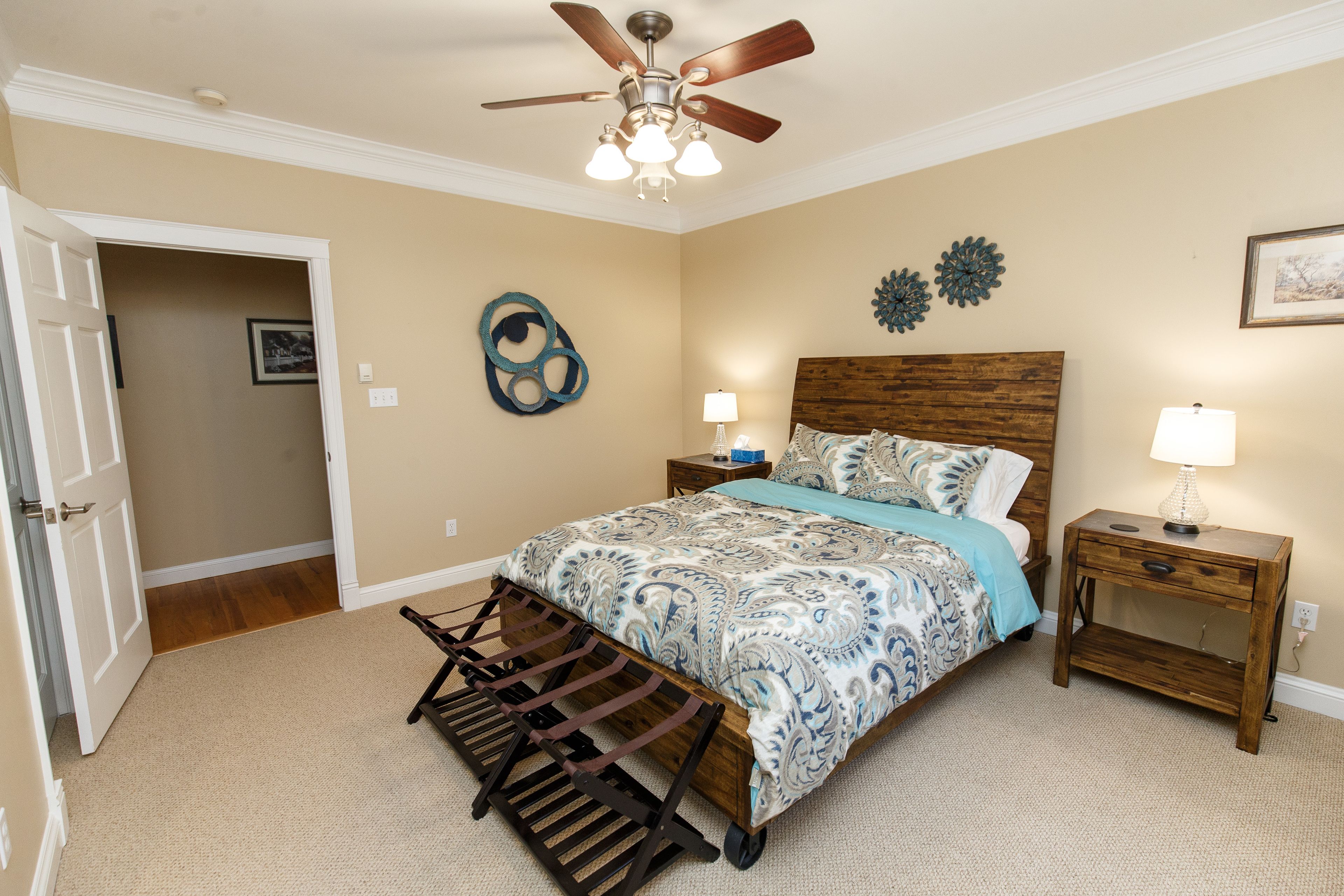 A bedroom with a bed, bedside tables, a ceiling fan, and a wall decor piece.
