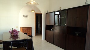 A dining area with a table and chairs, a sofa, and a cabinet with shelves. - Apartment/ flat - POSADA (Posada)