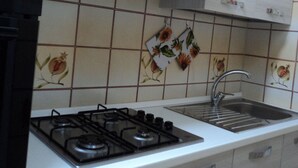 A kitchen with a gas stove, a sink, and a shelf with a red coffee pot and two white containers. - Apartment/ flat - POSADA (Posada)