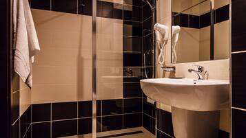 Ein modernes Badezimmer mit einer begehbaren Glasdusche, einem weißen Waschbecken und einem Handtuch an der Wand.