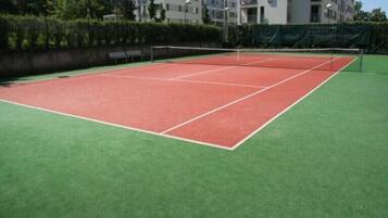 Een tennisbaan met een net in het midden, omgeven door een groene ondergrond.