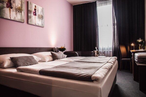 A hotel room with a large bed, a desk, and a window with curtains. - Interhotel Zlin (Zlin)