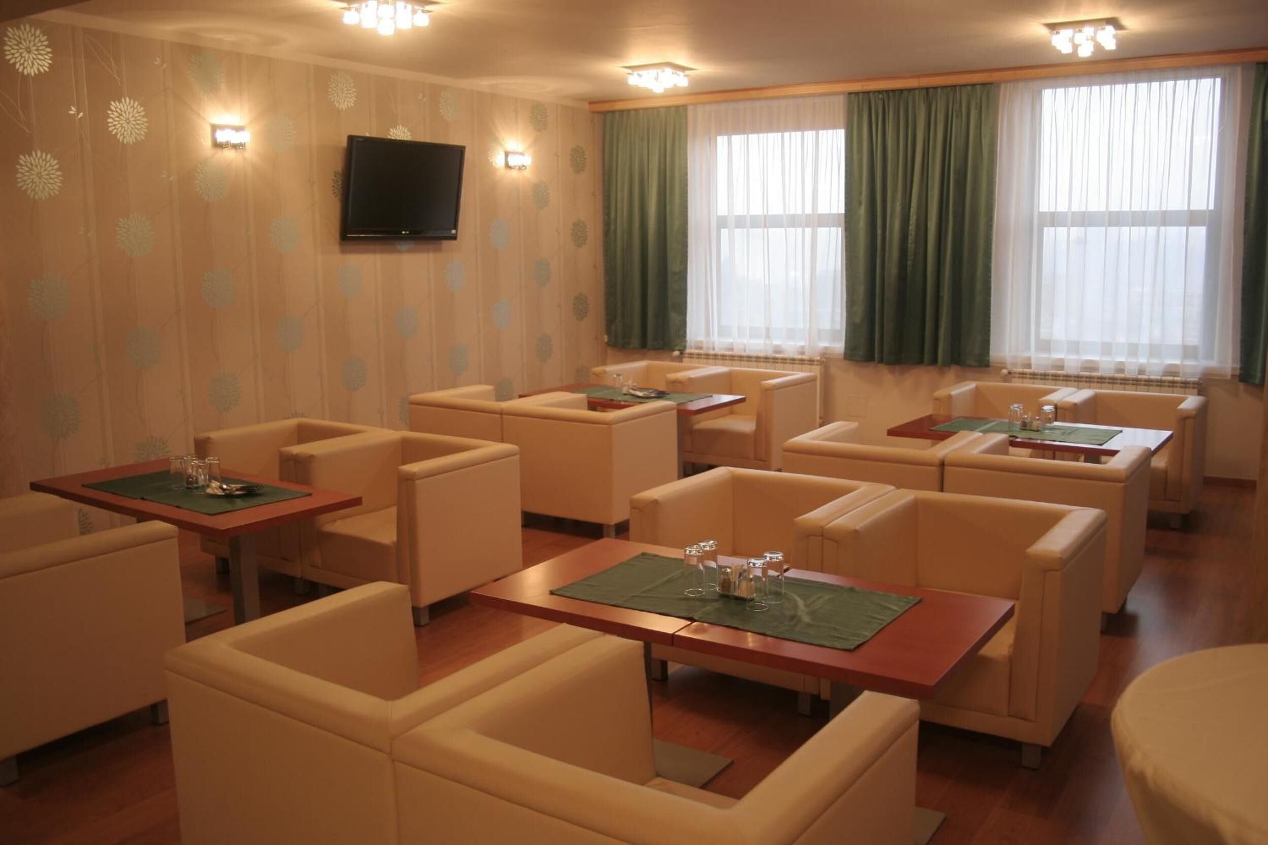 Een hotelkamer met meerdere zithoeken, waaronder banken en tafels, gerangschikt rond een centraal gelegen open haard.