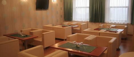 A hotel room with multiple seating areas, including sofas and tables, arranged around a central fireplace.