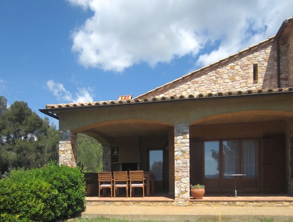 A stone building with a covered patio, outdoor seating, and a large window.