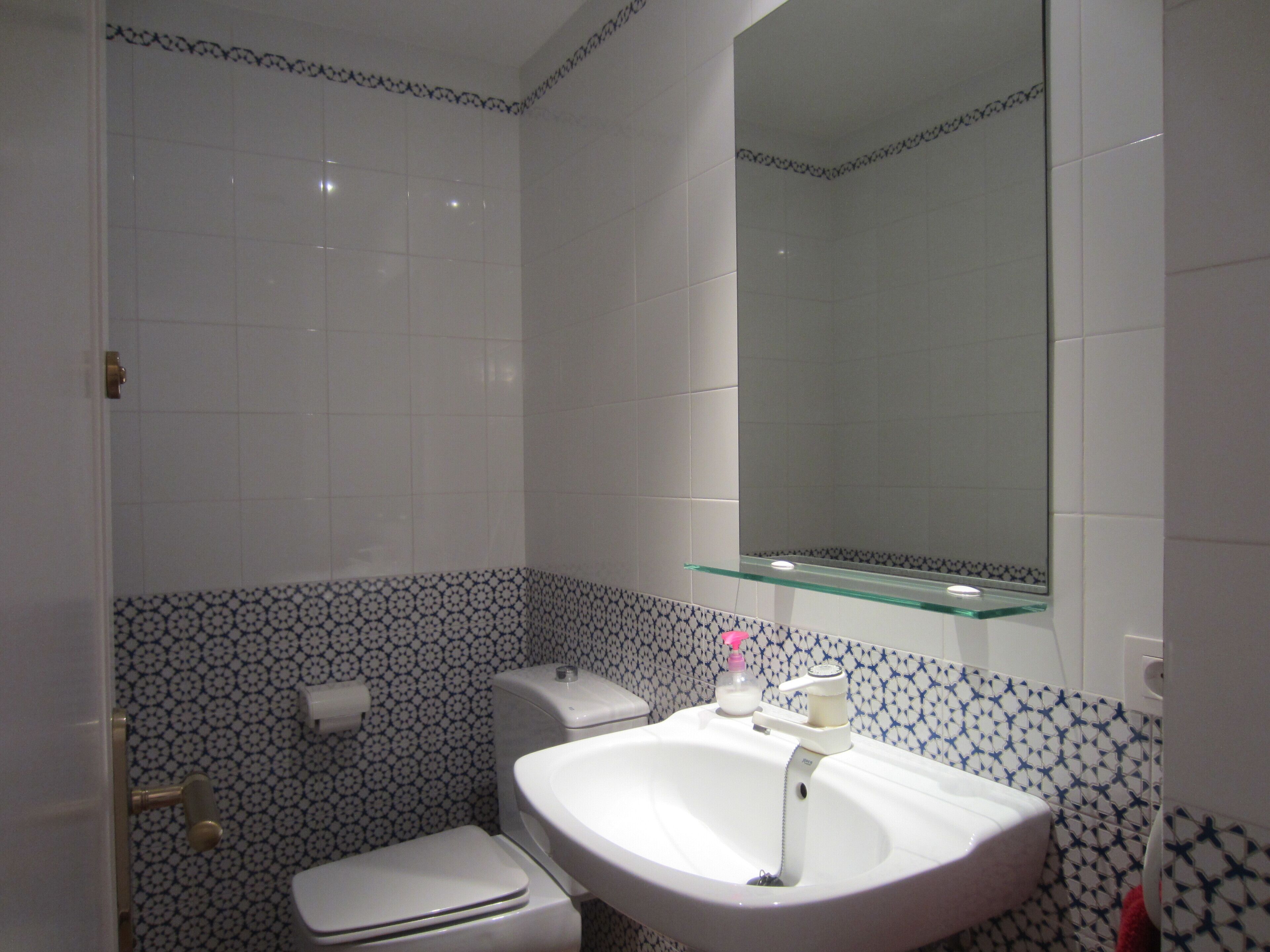 A bathroom with a toilet, sink, and mirror.