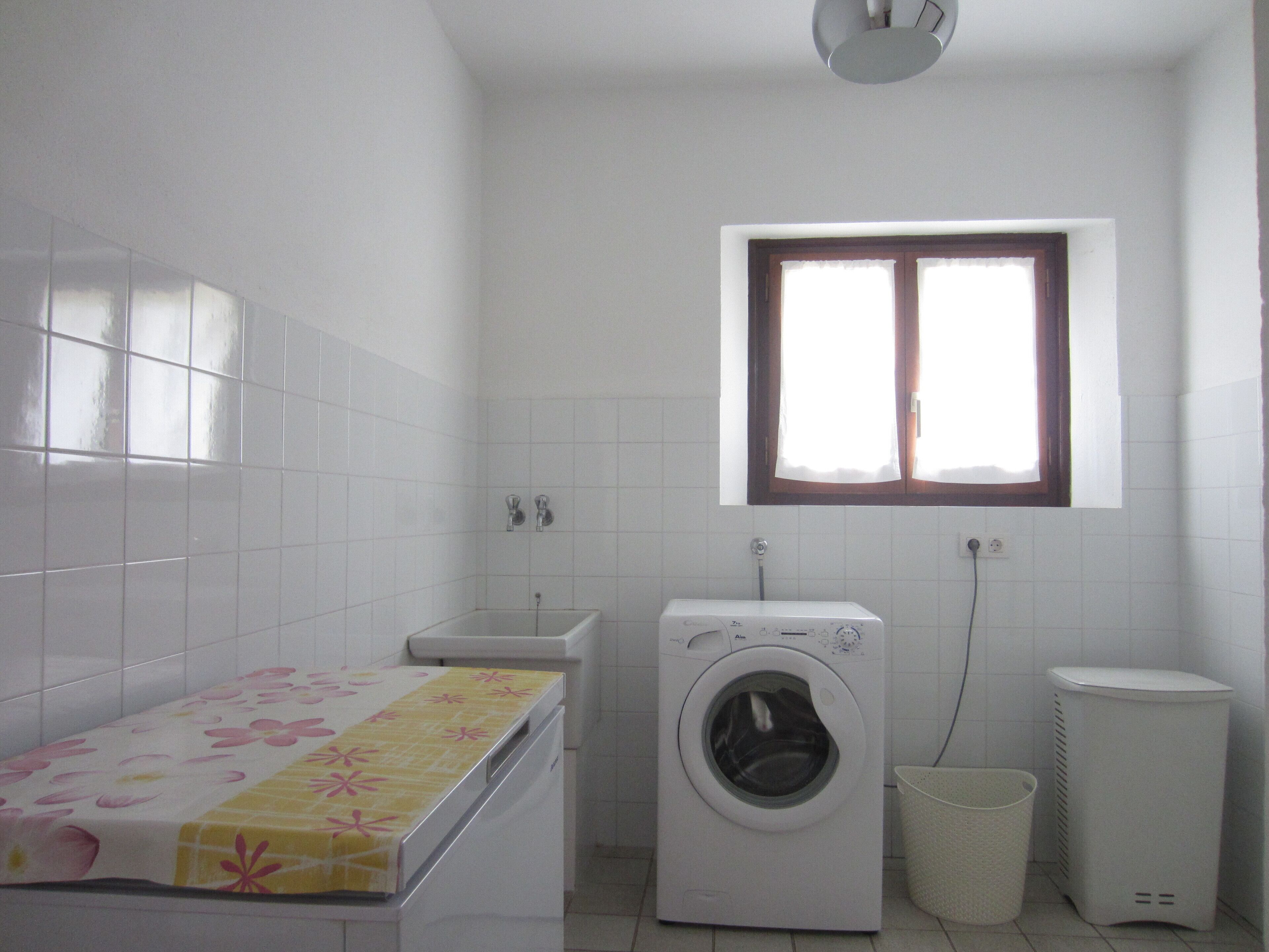 A laundry room with a washing machine, a dryer, a sink, and a window.