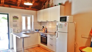A kitchen with white cabinets, a built-in oven, a microwave, and a refrigerator. - Mareta apartment with free wifi in a stone house (Seline)