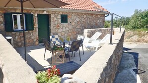 A stone house with a tiled roof, outdoor seating with chairs and a table, and a potted plant. - Mareta apartment with free wifi in a stone house (Seline)