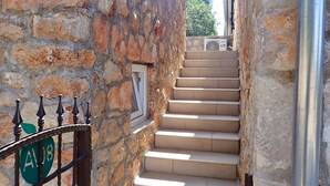 A stone staircase leading up to a door, with a metal gate and a green sign with the number 18. - Mareta apartment with free wifi in a stone house (Seline)