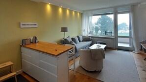 Una sala de estar moderna con un escritorio de madera, sofá y vistas al exterior a través de amplios ventanales.