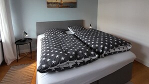 Un dormitorio con una cama, una mesita de noche, una lámpara y un cuadro en la pared.