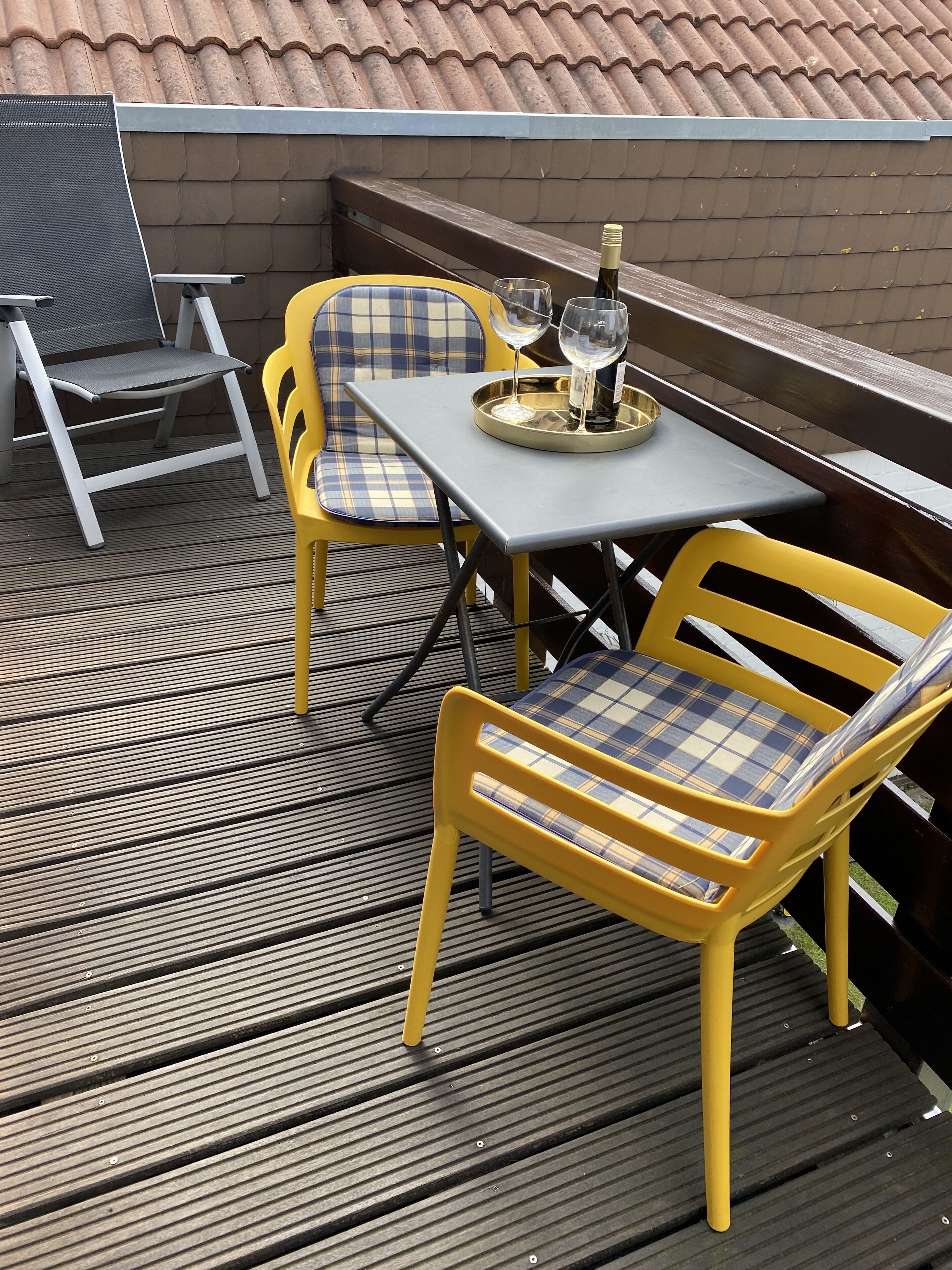 Un patio exterior con una mesa, sillas, una botella de vino y una bandeja.