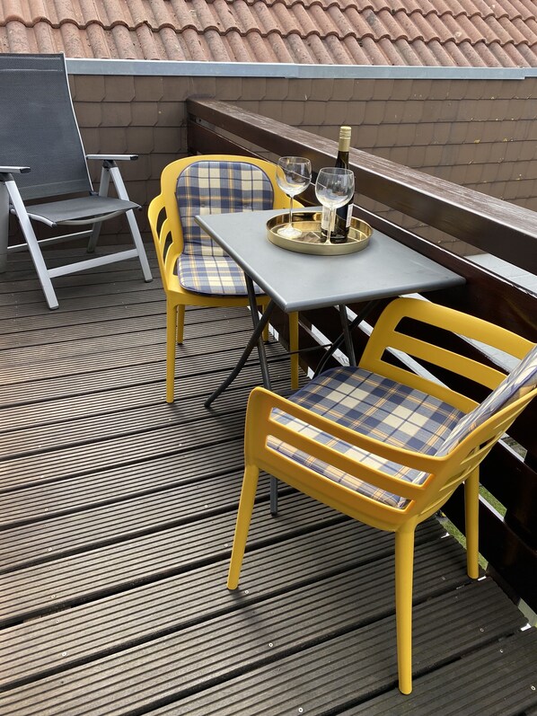 Un patio exterior con una mesa, sillas, una botella de vino y una bandeja.